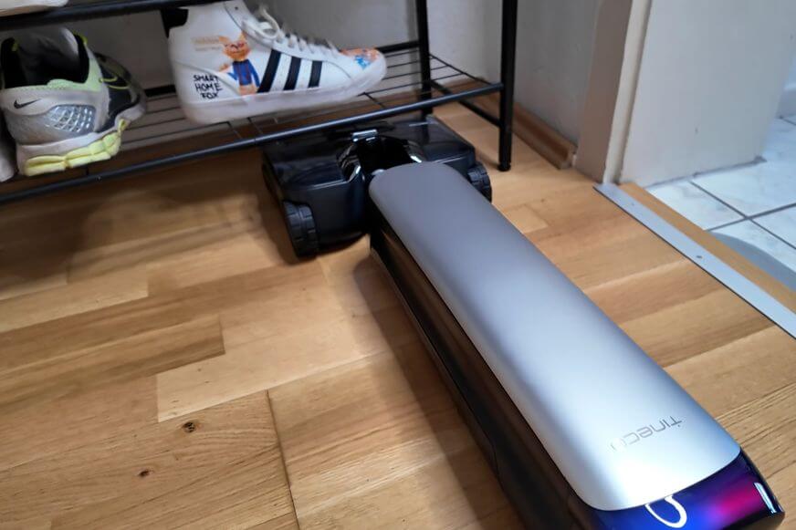 Tineco S9 Artist flach unter einem Möbelstück beim Wischen – zeigt 180° Flexibilität und geringe Bauhöhe.